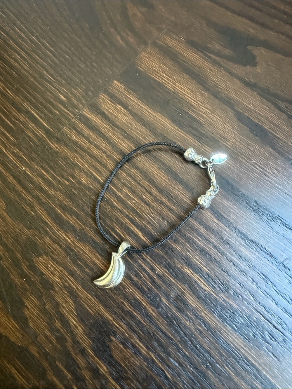 The Limited black cord bracelet with a textured, curved silver pendant